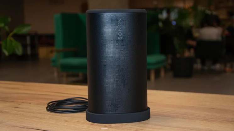 The black Sonos Play speaker in its charging dock on a wooden table