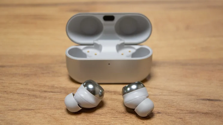 The Technics EAH-AZ100 wireless earbuds in front of their charging case with the lid open