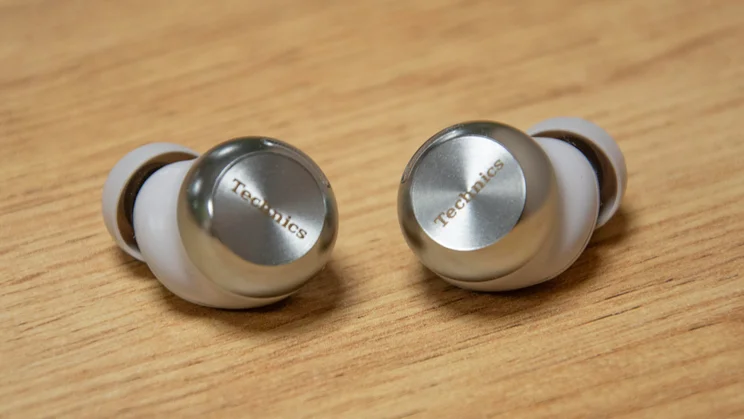 The Technics EAH-AZ100 wireless earbuds side by side on a wooden table