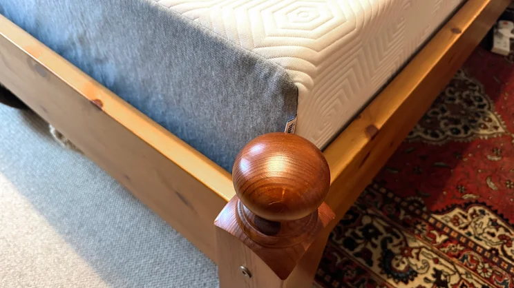 The corner of the TEMPUR EASE mattress, on a wooden bed frame