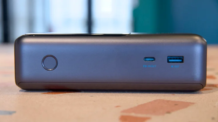 The Anker laptop power bank A1695 on its back, pictured from the left, showing the button (left) and two ports (right)