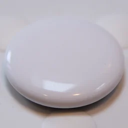 The Apple AirTag (2nd gen) pictured on a white rubber surface