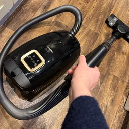 The Miele Guard L1 pictured vacuuming in a kitchen with a dark wood floor