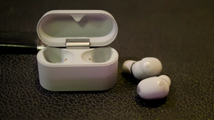 The Sony WF-1000XM6 pictured next to their charging case, open