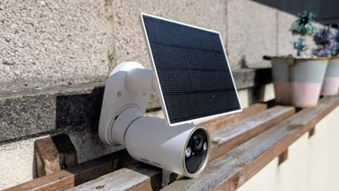 The Tapo C460 security camera pictured set on a wood shelf from the left side