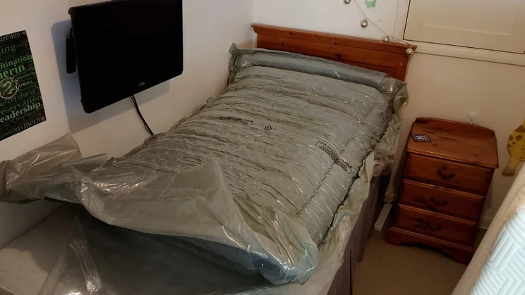 The Zoma Hybrid mattress unrolled in its packaging on a single divan bed frame