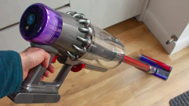 A Dyson cordless vacuum cleaner on a hardwood floor