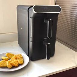 The Tower Vortx 11 Litre Dual Layer air fryer on a kitchen counter, alongside a plate of cooked hash browns