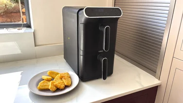 The Tower Vortx 11 Litre Dual Layer air fryer on a kitchen counter, alongside a plate of cooked hash browns