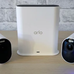 Two Arlo Ultra 3 security cameras, pictured with their smart hub