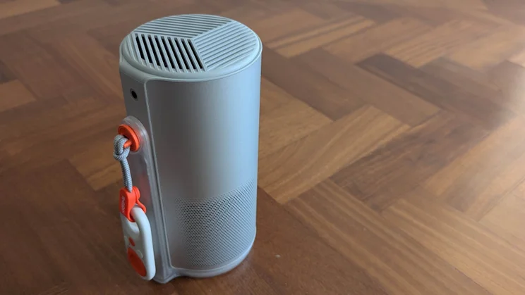 The XGIMI MoGo 4 Laser in Bluetooth speaker mode on a wooden floor with its mini remote control attached via a lanyard