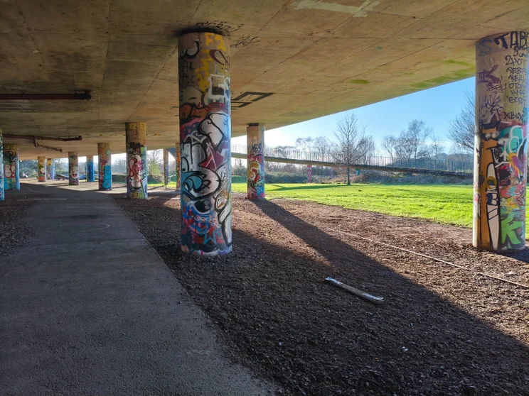 Graffiti-covered columns underneath a bridge