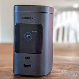 The Ugreen PB771 shown from the front on a wood table with the screen on